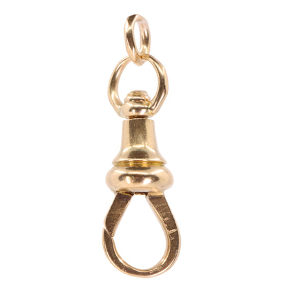 A polished gold-tone clasp charm pendant with a top loop and a teardrop-shaped bottom clasp, shown against a plain light pink background.